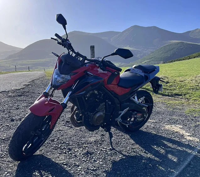 Moto rouge garée sur route de montagne.